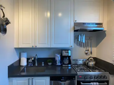 a kitchen with white cabinets and a stove top oven at Fern House South Park Craftsman in San Diego