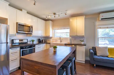 a kitchen with white cabinets and a wooden table at Fern House South Park Craftsman in San Diego