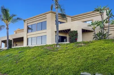 a building on a hill with palm trees in front of it at Buena Creek Vista Primary Subdivided Home with Views and Pool in San Marcos