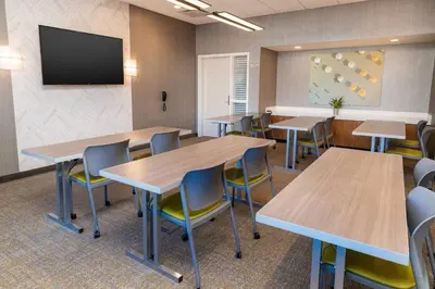 a classroom with tables and chairs and a tv at SpringHill Suites by Marriott Irvine Lake Forest in Lake Forest