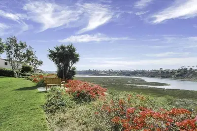 a bench sitting on the grass next to a river at 1000#2 Magnificent Beach Home w/ AC & 4K TVs in Newport Beach