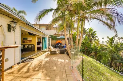 a patio with palm trees and a house at Tropical Oceanside Home with Deck, Walk to Beach in Oceanside