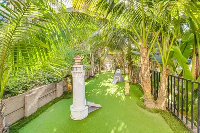 a garden with a lighthouse and palm trees at Tropical Oceanside Home with Deck, Walk to Beach in Oceanside