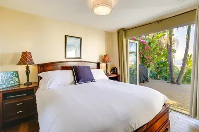 a bedroom with a large bed and a sliding glass door at Tropical Oceanside Home with Deck, Walk to Beach in Oceanside