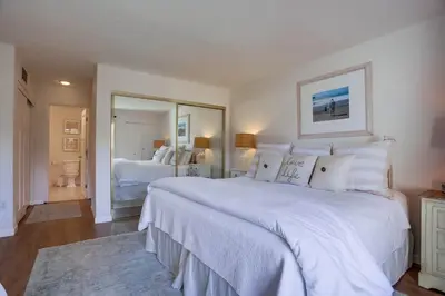 a white bedroom with a large bed and a mirror at Coastal Chic Style Condo SBTC 128 in Solana Beach