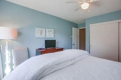 a bedroom with a white bed and a desk with a computer at Coastal Chic Style Condo SBTC 128 in Solana Beach