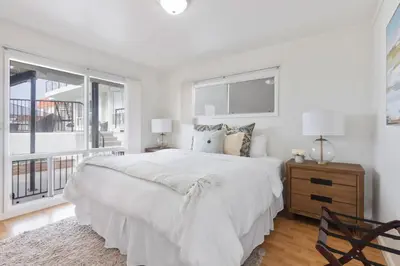 a white bedroom with a large bed and a window at Victoria #5 in San Clemente