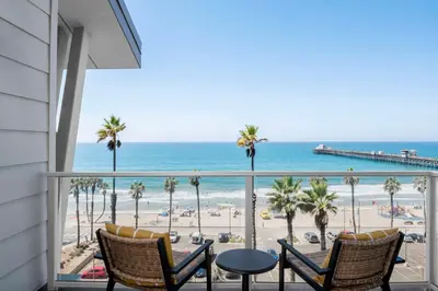 a balcony with a view of the beach and palm trees at The Seabird Ocean Resort & Spa, Part of Destination Hotel by Hyatt in Oceanside