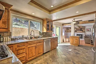 a large kitchen with wooden cabinets and a large window at Spacious El Cajon Villa - 14 Mi to Downtown! in El Cajon