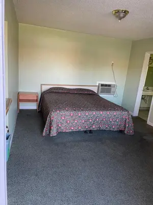 a bedroom with a bed with a blanket on it at RAMONA MOTEL in Hemet