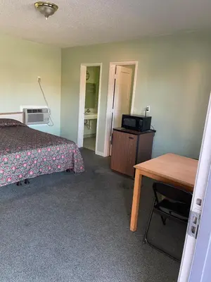 a bedroom with a bed and a desk and a table at RAMONA MOTEL in Hemet
