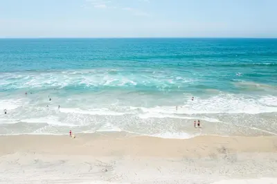 a group of people in the water at the beach at The Marbella in Oceanside