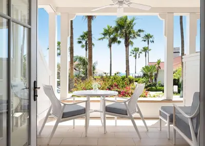 a patio with a table and chairs and palm trees at Beach Village at The Del, LXR Hotels & Resorts in San Diego