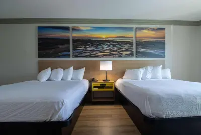 two beds in a hotel room with paintings on the wall at Days Inn by Wyndham Carlsbad in Carlsbad