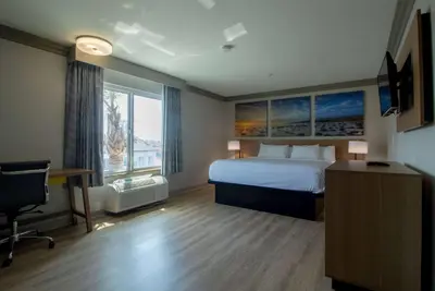 a hotel room with a bed and a desk and a television at Days Inn by Wyndham Carlsbad in Carlsbad