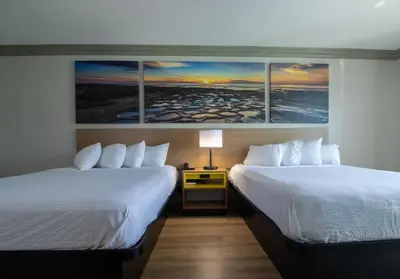 a hotel room with two beds and a painting on the wall at Days Inn by Wyndham Carlsbad in Carlsbad