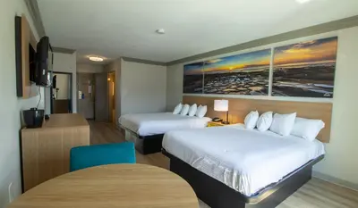 a hotel room with two beds and a table at Days Inn by Wyndham Carlsbad in Carlsbad