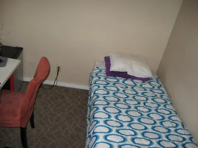 a small bedroom with a bed and a desk and a chair at RK Hostel in San Diego