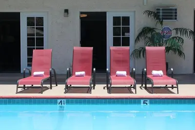 four red chairs sitting next to a swimming pool at California Suites Hotel in San Diego
