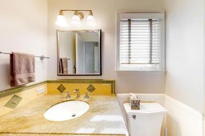 a bathroom with a sink and a mirror and a toilet at Sycamore Beach Retreat in Carlsbad