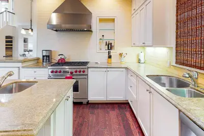 a kitchen with white cabinets and stainless steel appliances at Sycamore Beach Retreat in Carlsbad