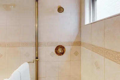 a bathroom with a shower with a towel and a window at Luxury Oceanfront Home - Lower in Oceanside