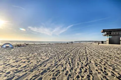 a sandy beach with a building and the ocean at San Diego Hub with Bay Views - 1 Block to Beach! in San Diego