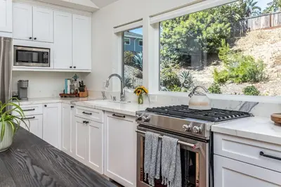 a kitchen with white cabinets and a stove and a window at 727 Sonrisa St home in Solana Beach