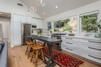 a kitchen with white cabinets and a table and chairs at 727 Sonrisa St home in Solana Beach