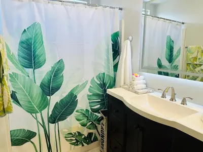 a bathroom with a shower curtain with large leaves at Balloons and Wine in Murrieta