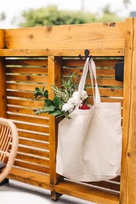 a white bag hanging on a wooden stand with flowers at The Green Room Hotel in Oceanside