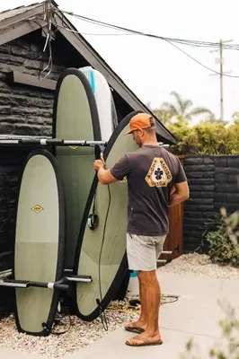 a man is putting his surfboard in a rack at The Green Room Hotel in Oceanside