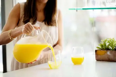 a woman pouring an orange juice into a glass at Hyatt House San Diego Sorrento Mesa in Sorrento