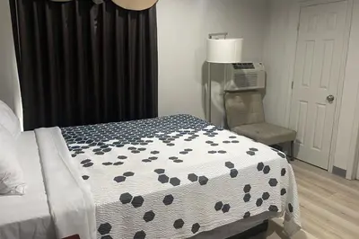 a bedroom with a bed and a chair and a window at Big 7 Motel Chula Vista I-5 in Chula Vista