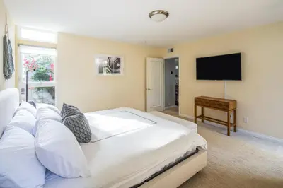 a bedroom with a bed with white pillows and a flat screen tv at Beach Resort Home with Ocean Views Jacuzzi & Sauna! in San Diego