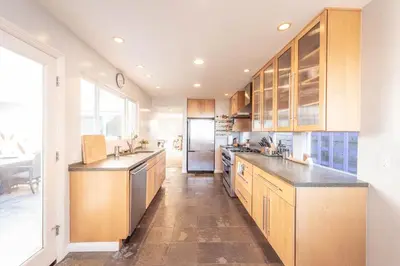 a large kitchen with wooden cabinets and a refrigerator at Beach Resort Home with Ocean Views Jacuzzi & Sauna! in San Diego