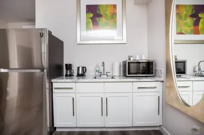 a kitchen with white cabinets and a stainless steel refrigerator at Comfy Studio with Cali King Size Mattress in San Diego