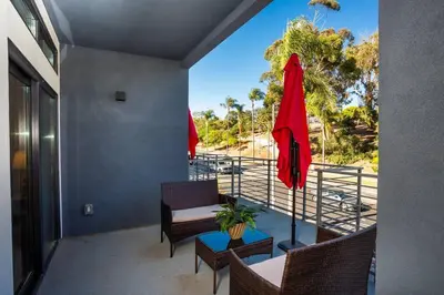 a balcony with chairs and a table and a red umbrella at Awesome Balboa Park View with Huge Balcony in SD in San Diego
