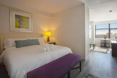 a bedroom with a large white bed with a purple bench at Luxurious Design One Bedroom Apt near Balboa Park in San Diego
