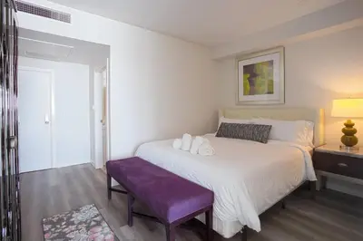 a bedroom with a large bed and a purple bench at Luxurious Design One Bedroom Apt near Balboa Park in San Diego