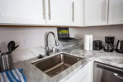 a kitchen with a stainless steel sink and white cabinets at Luxurious Furnished Studio w Full Kitchen in SD in San Diego