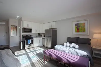 a bedroom with a large bed and a kitchen at Luxurious Furnished Studio w Full Kitchen in SD in San Diego