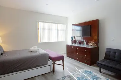 a bedroom with a bed and a tv and a chair at Luxurious Furnished Studio w Full Kitchen in SD in San Diego