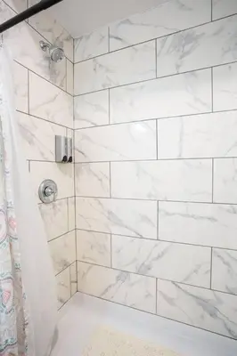 a bathroom with a shower with white marble tiles at Cute Studio With Large Balcony and Great Park View in San Diego