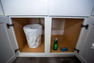 a cabinet with a trash can and a bottle in it at One Bedroom Apartment with SD Downtown View in San Diego
