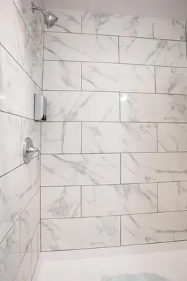 a bathroom with a shower with white marble tiles at Cali King Size One Bedroom Luxurious Suite in DTSD in San Diego