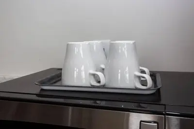 three white mugs sitting on a tray on top of a microwave at Cali King Size One Bedroom Luxurious Suite in DTSD in San Diego