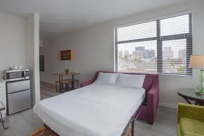a bedroom with a large white bed and a kitchen at Cali King Size One Bedroom Luxurious Suite in DTSD in San Diego