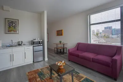 a living room with a purple couch and a kitchen at Cali King Size One Bedroom Luxurious Suite in DTSD in San Diego