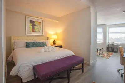 a bedroom with a large white bed with a purple bench at Spacious 1 Bedroom Apartment in Balboa Park in San Diego